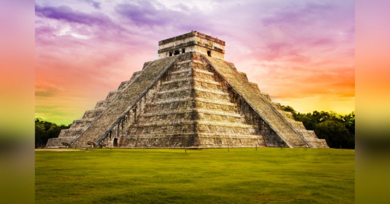 Imagem do topo de um templo maia em meio a céu com nuvens