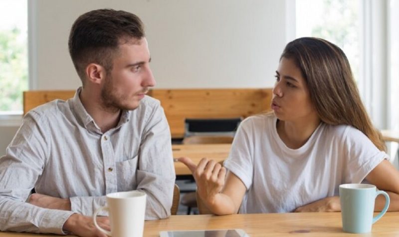 na foto, aparece um homem sentado ouvindo uma mulher sobre o que ela nunca deve contar a ninguém