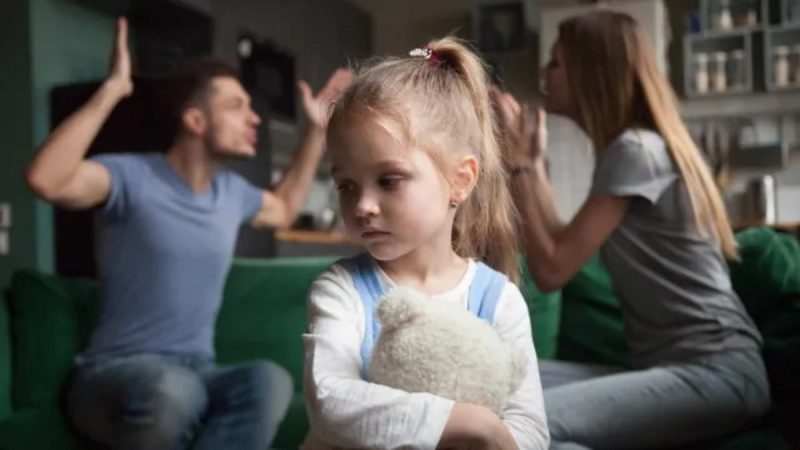 Menina que sofre com a parentificação ouvindo pais brigando