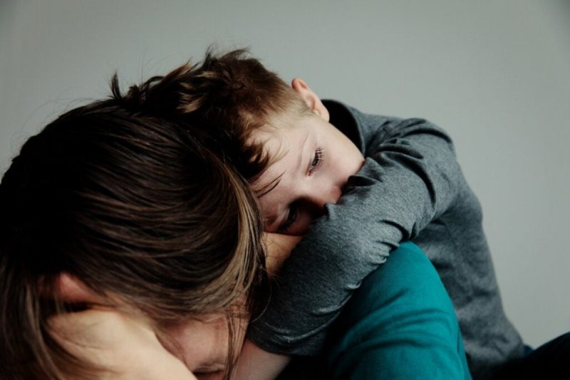 Menino que sofre com parentificação consolando a mãe