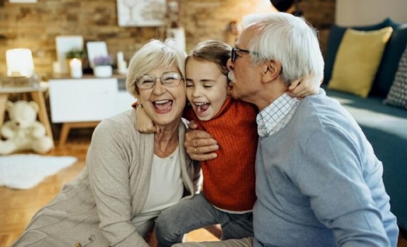 na foto aparece uma pessoa criada com os avós sorrindo após brincadeira