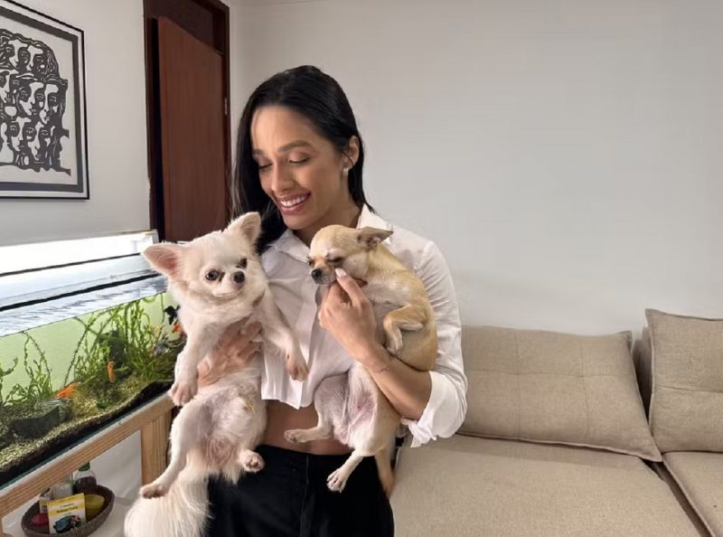 Eva com seus dois cachorros e o aquário ao fundo 