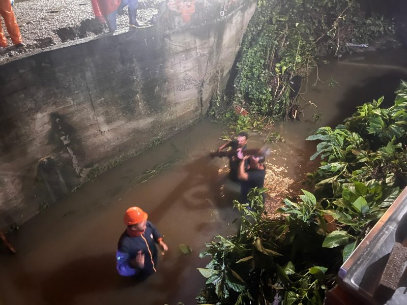 Foto mostra ruas submersas em Porto Belo, com agentes da defesa civil