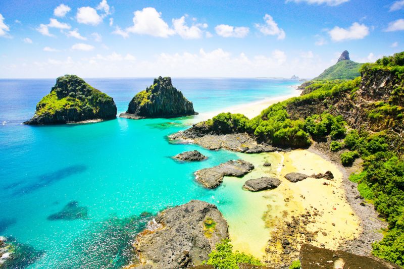 Imagem de uma praia com rochas e águas claras 