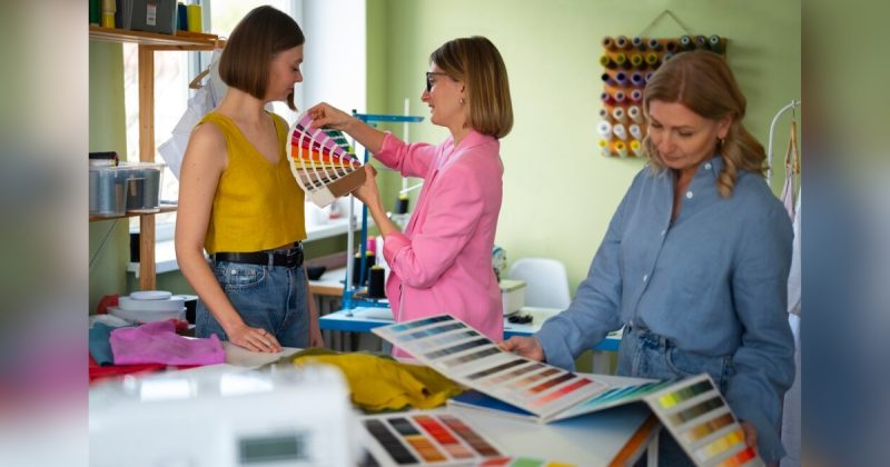 Mulher colocando paleta de cores no peito de outra, enquanto outra vê cores