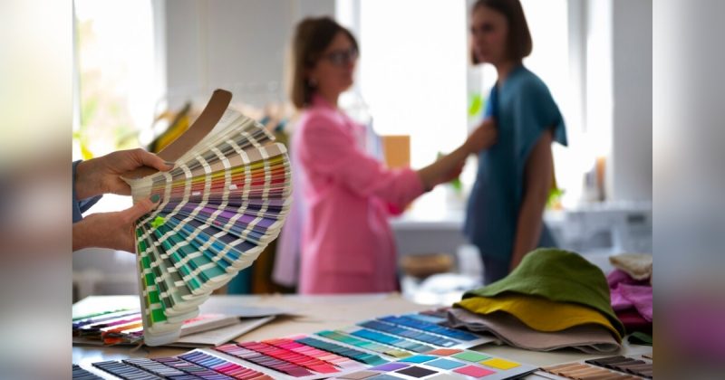 Mulher mostrando paleta de cores com duas outras mulheres no fundo