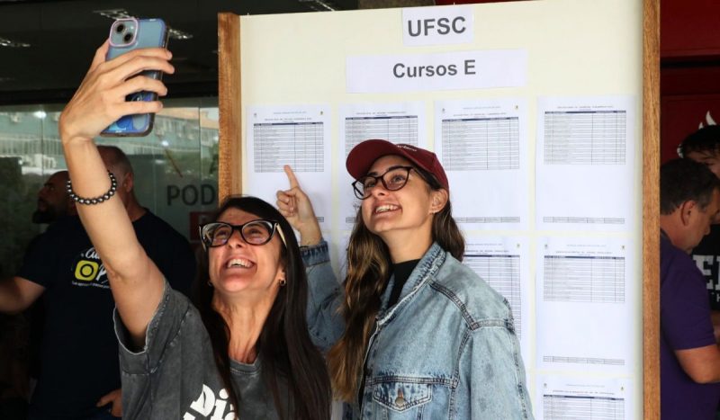 Candidata tira foto em frente ao mural com resultados do Vestibular Unificado UFSC/IFSC/IFC 202