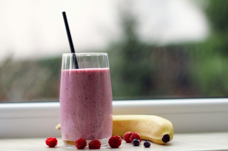 Batido de banana e frutos vermelhos próximo à janela