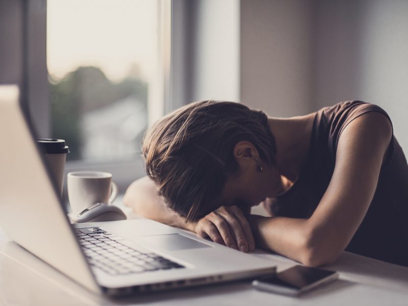 A imagem mostra uma mulher cansada no trabalho 