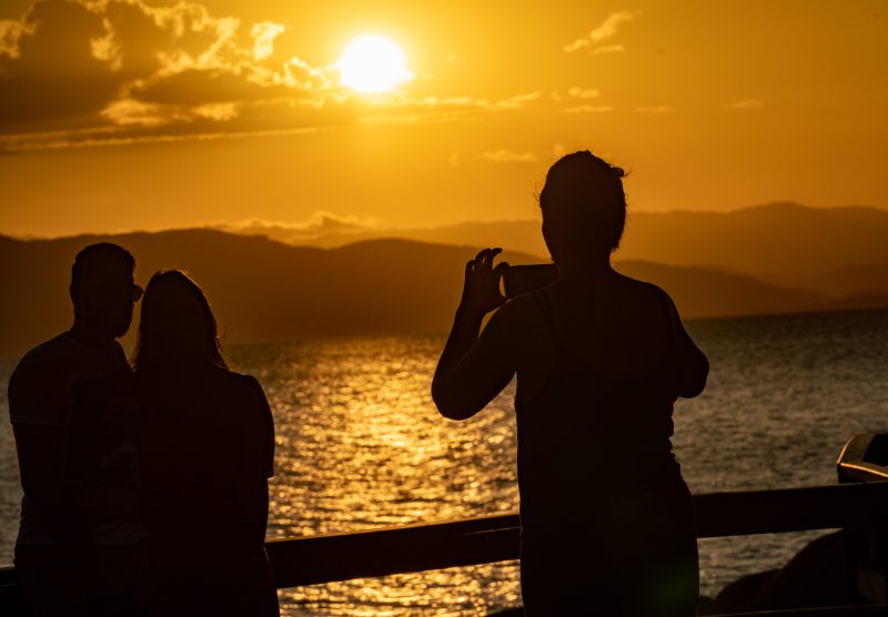 Pessoa tirando foto de casal em dia ensolarado, para ilustrar texto com o tema Até quando vai a onda de calor em Santa Catarina