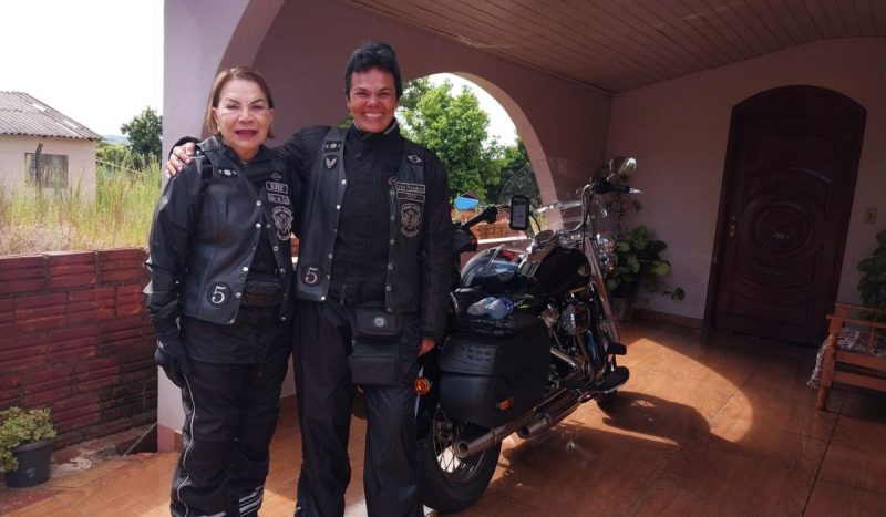 Mãe de 82 anos topa aventura de moto de 2463 km com filha pelo Sul do Brasil, foto mostra mãe e filha vestidas com roupas pretas para viagem, elas sorriem em frente a uma moto