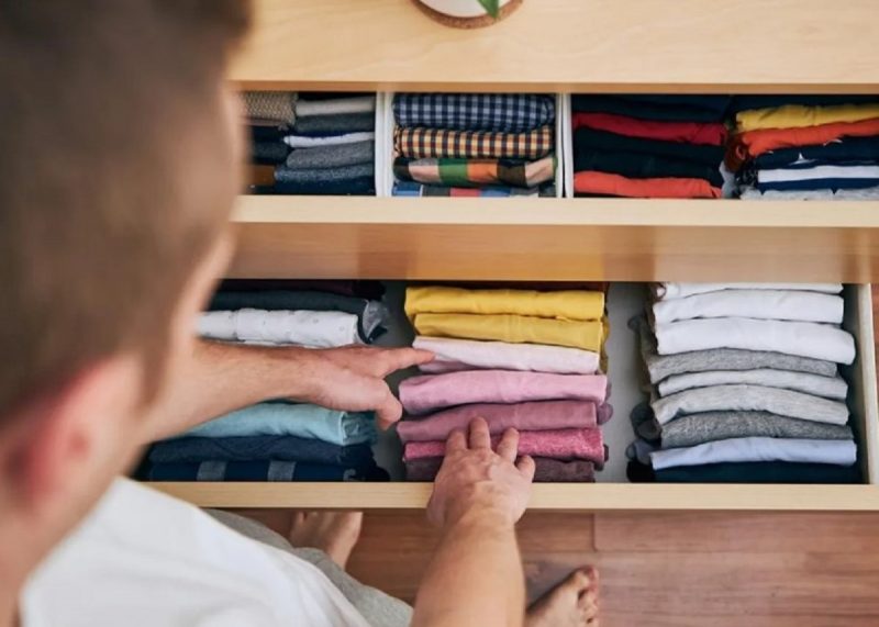 na foto mostra um homem viciado em limpeza que é organizado com roupas em gavetas