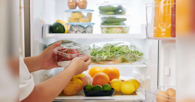 Pessoa colocando alimentos em geladeira com alimentos