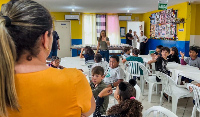 Foto de professora com estudantes em sala de aula