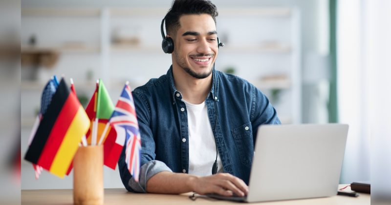 Homem na frente de computador com várias bandeiras 