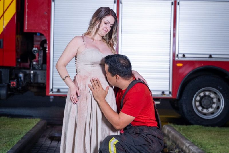 bombeiro beijando a barriga grávida da esposa; escolheram o nome da primeira filha