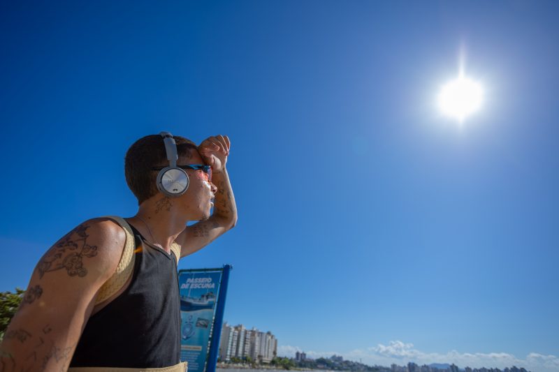 Onda de calor, foto mostra homem de fone suando em frente ao sol