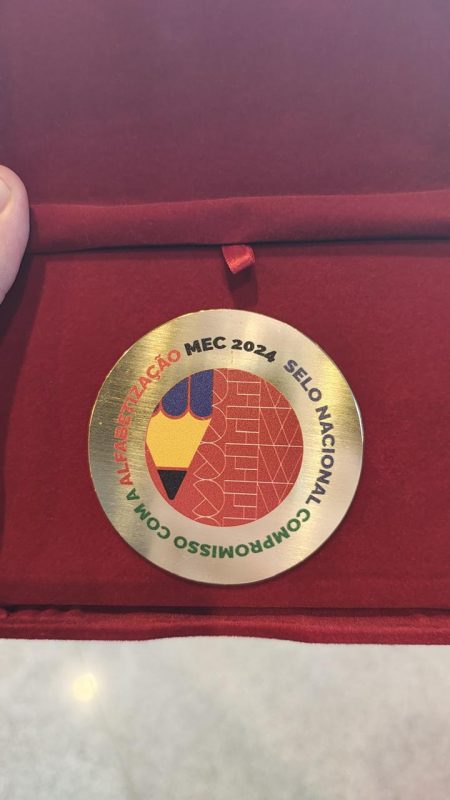 Foto mostra medalha de ouro do Selo Nacional Compromisso com a Alfabetização