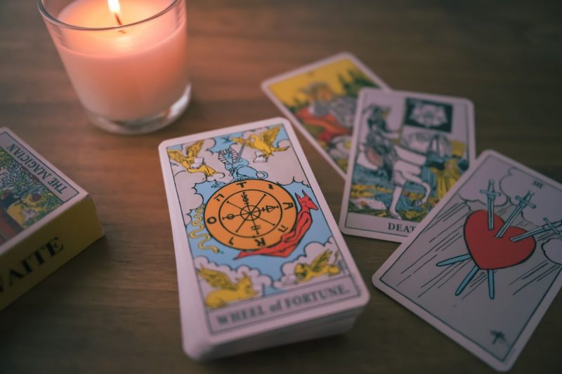 baralho de tarot em cima da mesa com uma vela acesa 