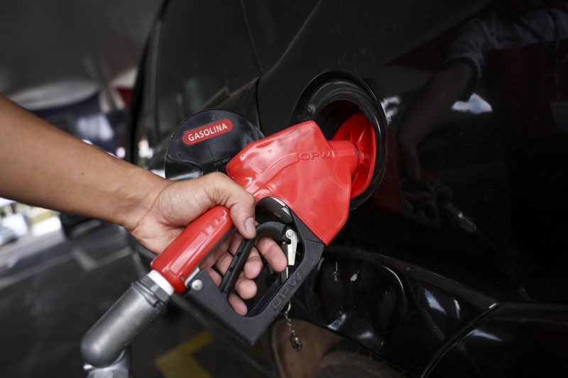 na foto aparece um homem abastecendo o carro e encher o tanque de gasolina