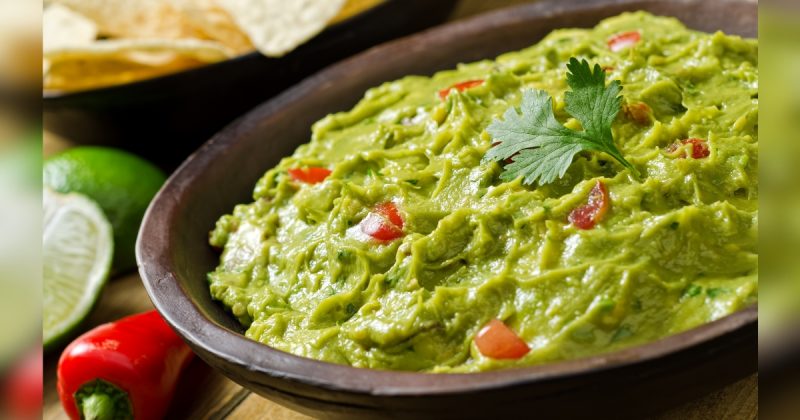 Prato guacamole dentro de tigela marrom com uma folha de salsa