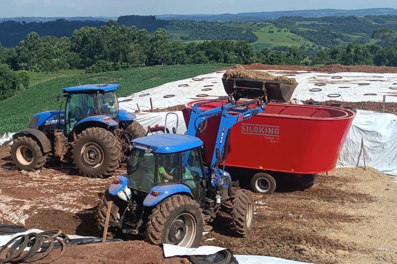 três máquinas agrícolas em uma área rural