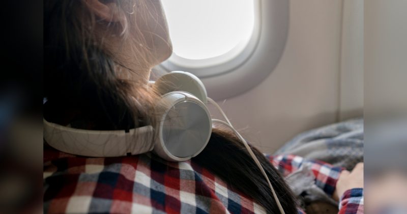 Pessoa de camisa quadriculada com fone de ouvido no pescoço dentro de avião