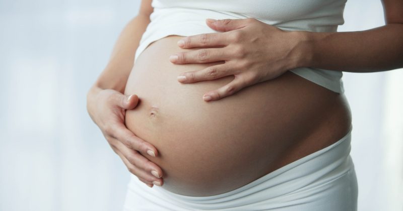 Mulher segurando barriga com mãos