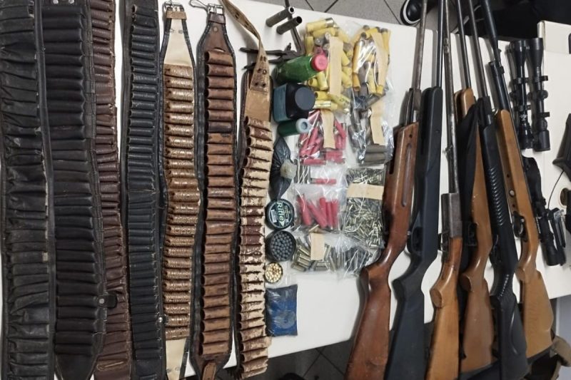 arsenal de armas em cima de uma mesa ao lado de munições e cintos de armas