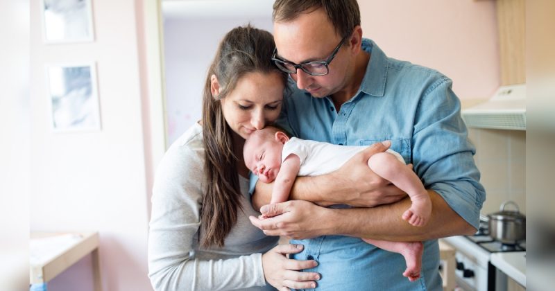 Homem e mulher segurando bebê no colo