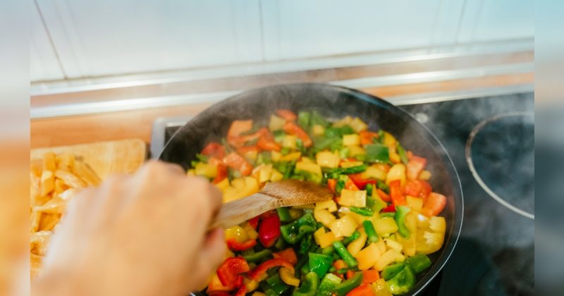 Pessoa cozinhando com verduras dentro de panela