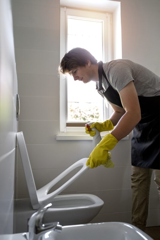 Homem limpando o vaso sanitário