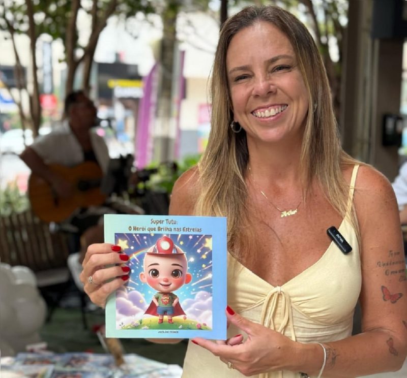 Mãe segurando livrinho que conta a história do filho durante lançamento 