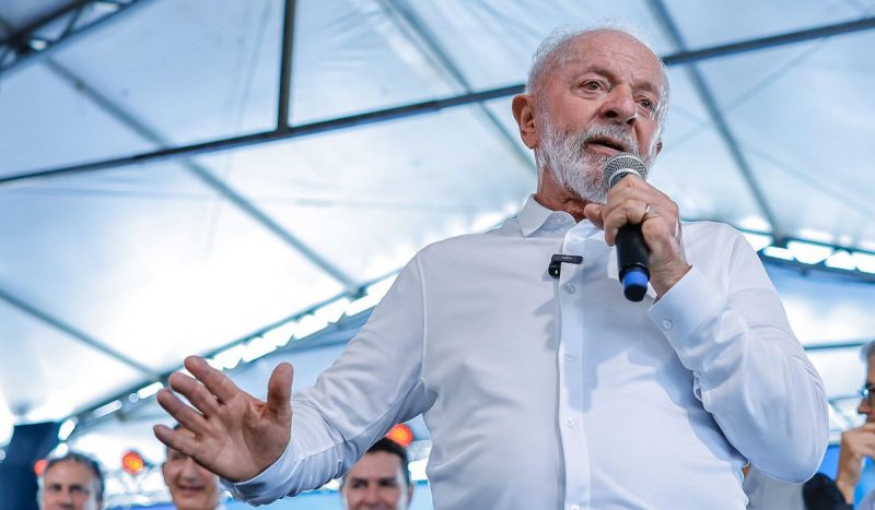 Foto do presidente Lula falando com microfone na mão durante evento