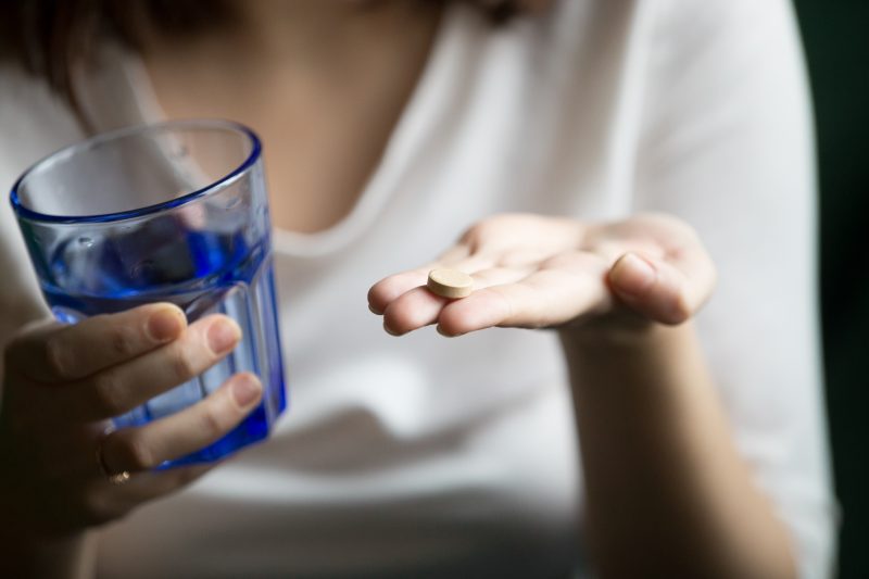 Mulher tomando magnésio com um copo de água