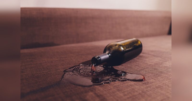 Garrafa de vinho caída em sofá
