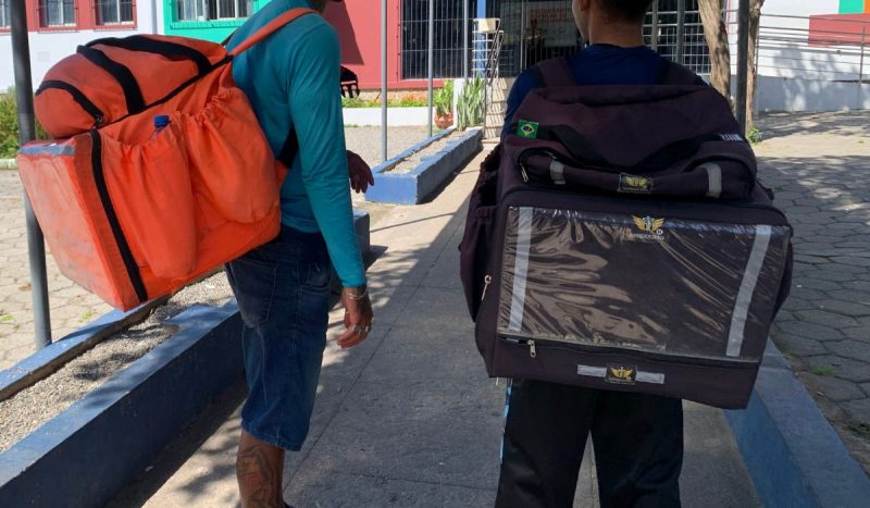 Homens com mochilas de entrega em frente ao Restaurante Popular de Florianópolis