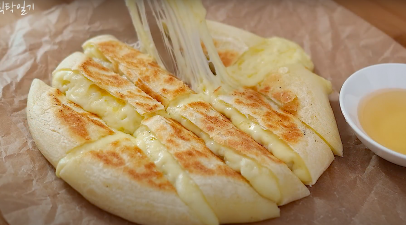 Foto mostra pão de batata e queijo cremoso prono e sendo cortado