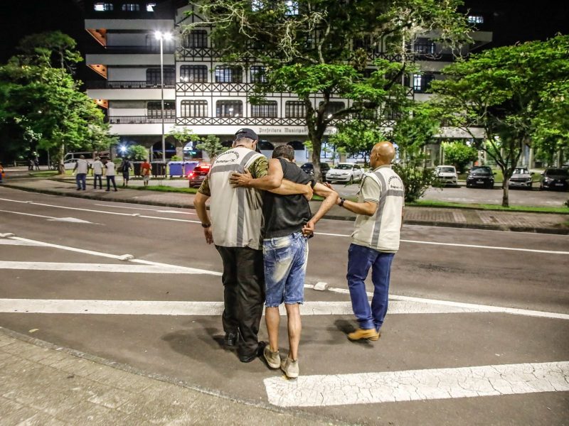 Servidores ajudando pessoa em situação de rua, em frete a prefeitura da cidade