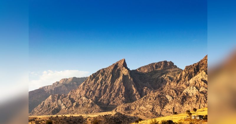 Montanha Zagros com rochas pontudas e vegetação ao redor e céu claro