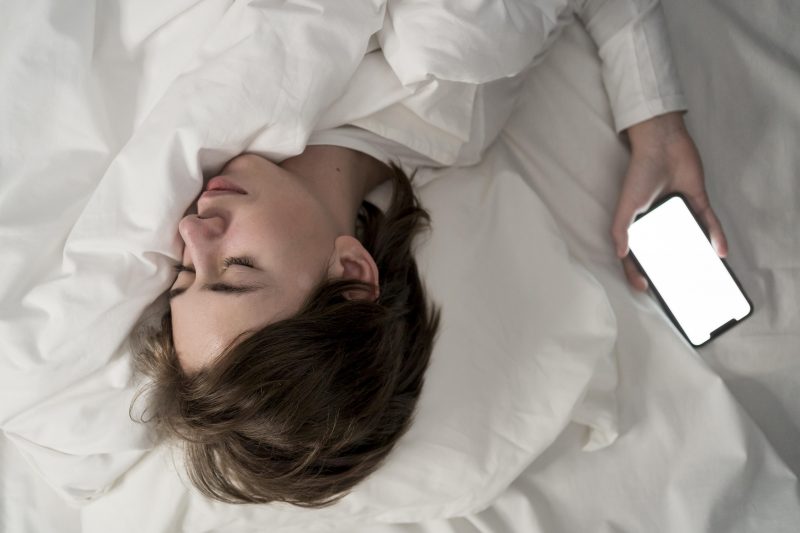 mulher ao dormir com celular ao lado da cama