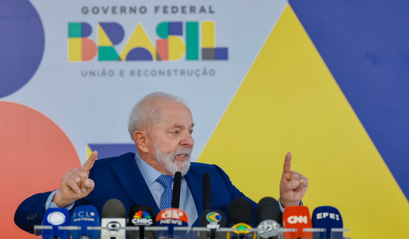 Presidente Lula com dedos em riste fazendo discurso com diversos microfones de empresas de comunicação na sua frente