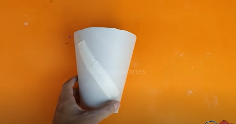 Primeiro passo de como fazer o vaso de luxo, formando um cone com papel cartão e cortando suas irregularidades .