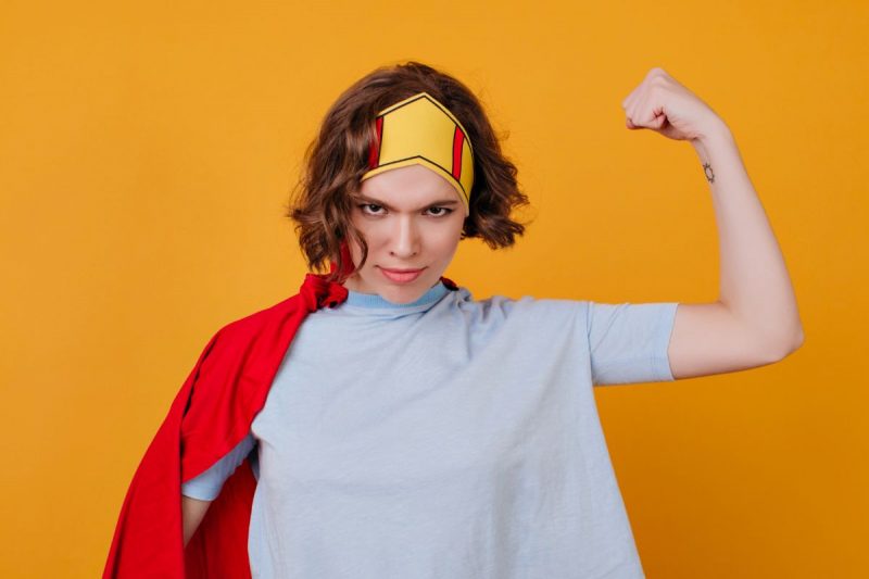 Mulher vestida com uma capa e uma faixa na cabeça como se tivesse um superpoder