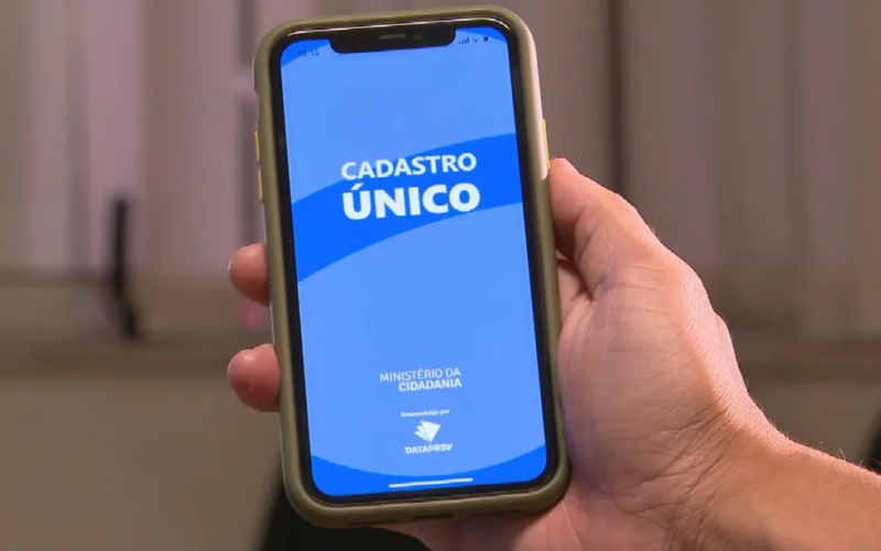 Mão segurando celular na tela inicial do aplicativo do Cadastro Único 