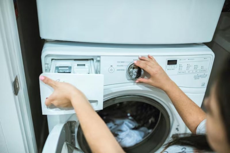 Mulher colocando vinagre branco no lugar do amaciante na máquina de lavar 