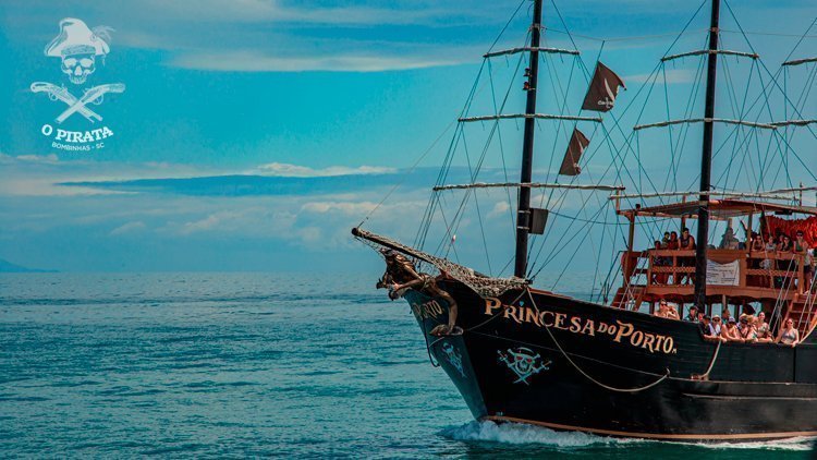 Na parte esquerda da foto, o mar e o céu azul. Do lado esquerdo, parte da proa de um barco preto, onde está escrito Princesa do Porto. 