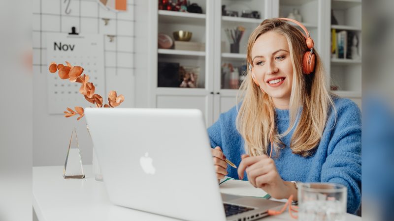 Mulher feliz olhando em computador com fones rosado