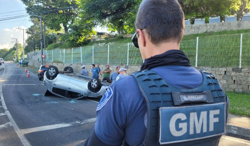 Carro capota no Itacorubi e congestiona trânsito em Florianópolis na manhã desta quinta-feira. Na imagem, o veículo capotado cercado de pessoas