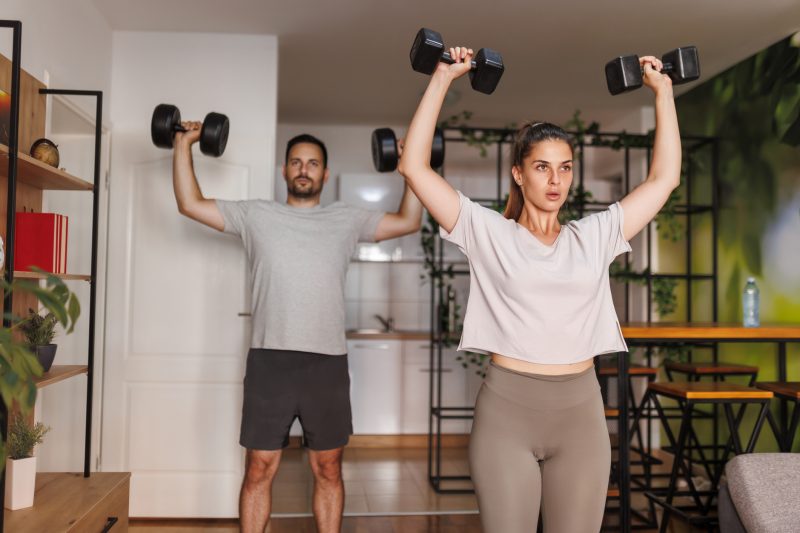 Casal treinando em casa com halteres